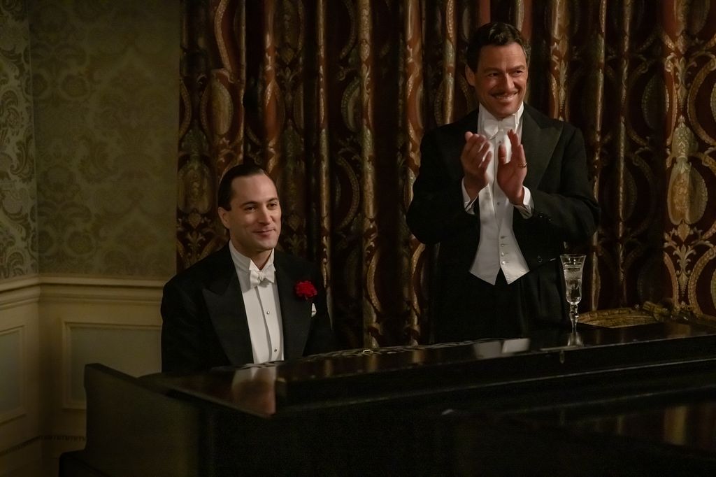 man in tuxedo playing piano, next to man standing in tuxedo