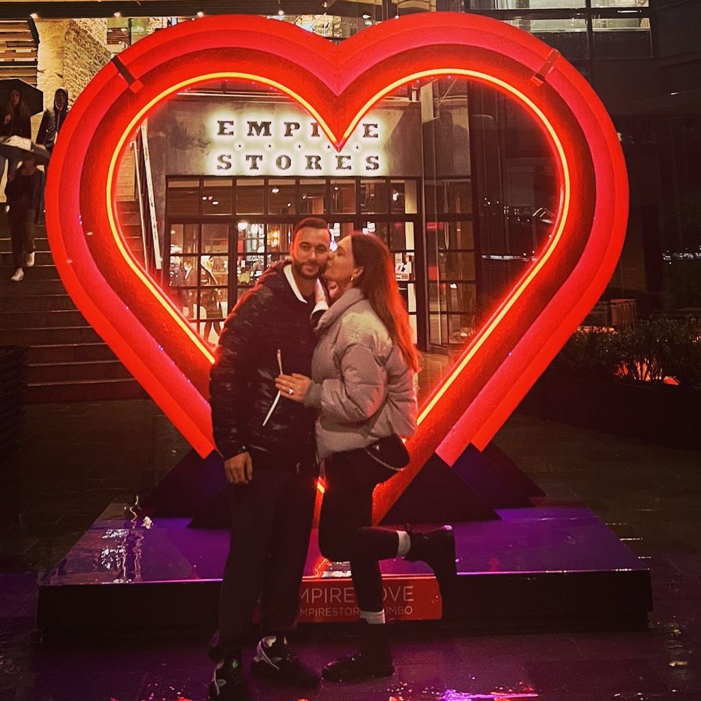 Nathan Mathers and his wife Ashley Mae Mathers pose for a photo in front of a lit heart sign, shared on Instagram