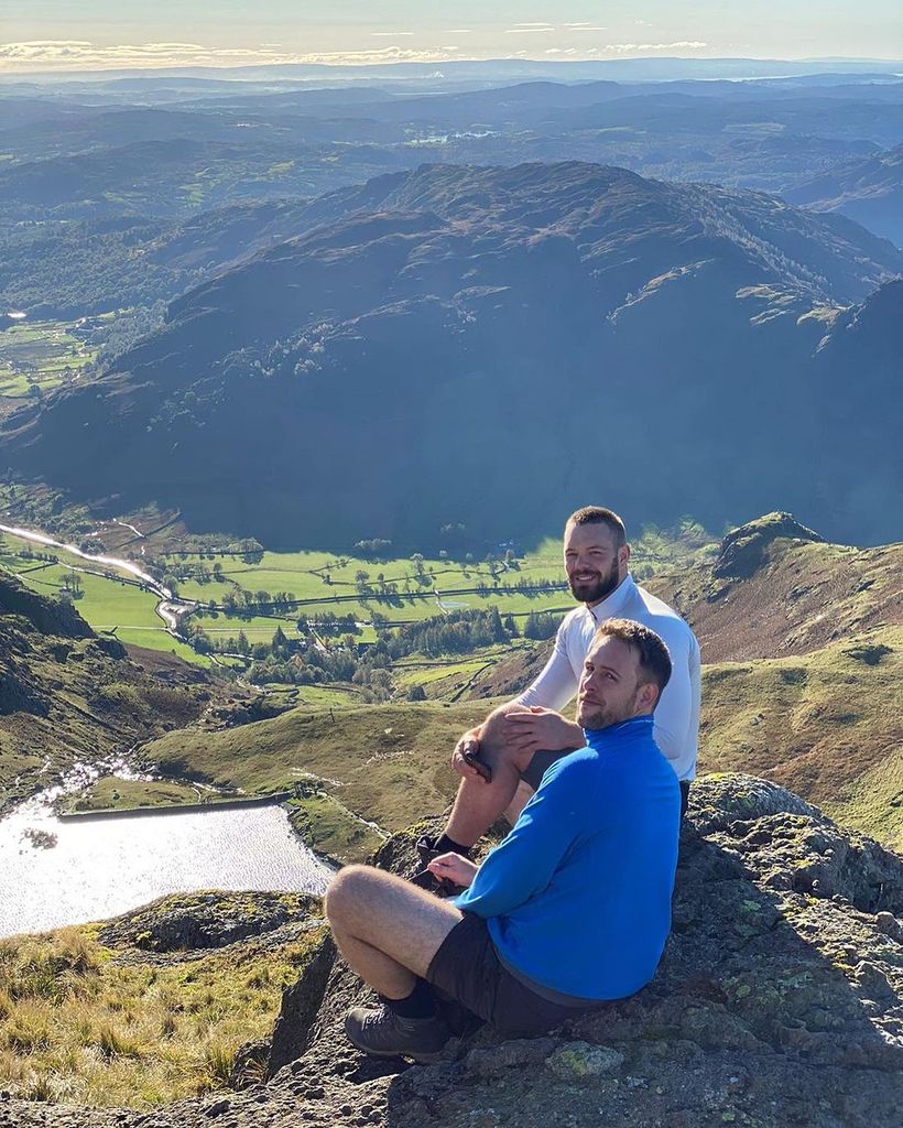 John Whaite and his fiance Paul sitting on top of a mountain