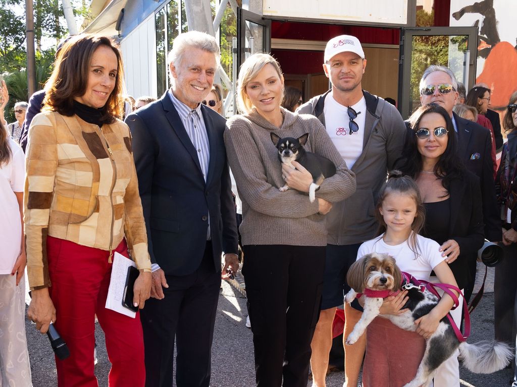 Princess Charlene in a taupe knitted hoodie with people holding dogs