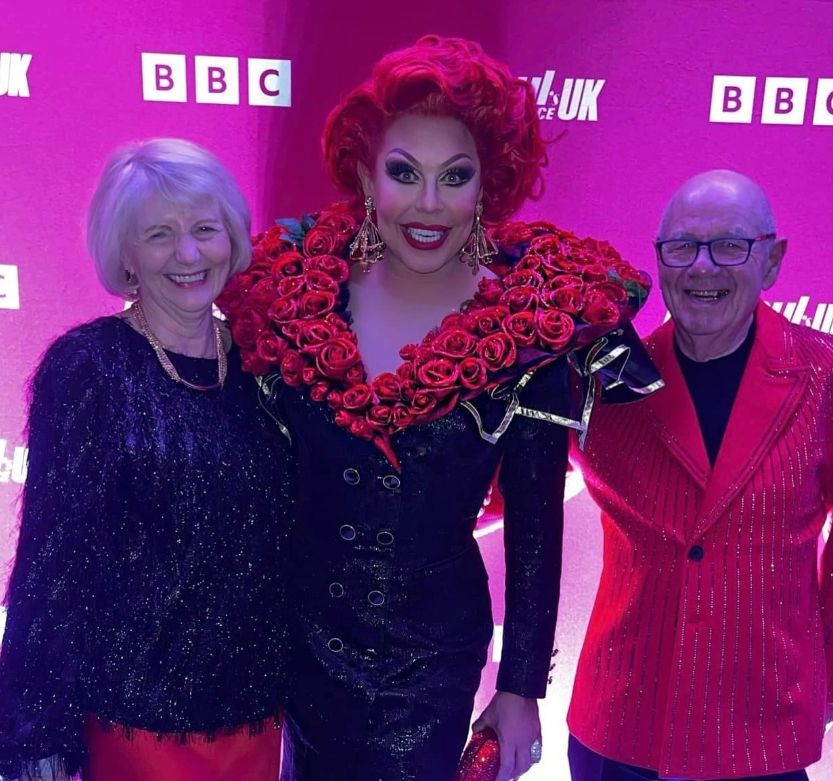 LA Voix in drag standing with her mother and father