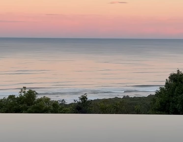 Elsa's swimming pool in the foreground with the Byron Bay coastline and sunset in the background