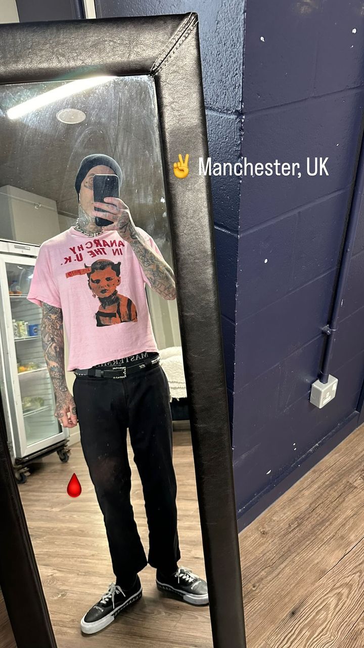 Travis Barker taking a mirror selfie in a pink T-shirt