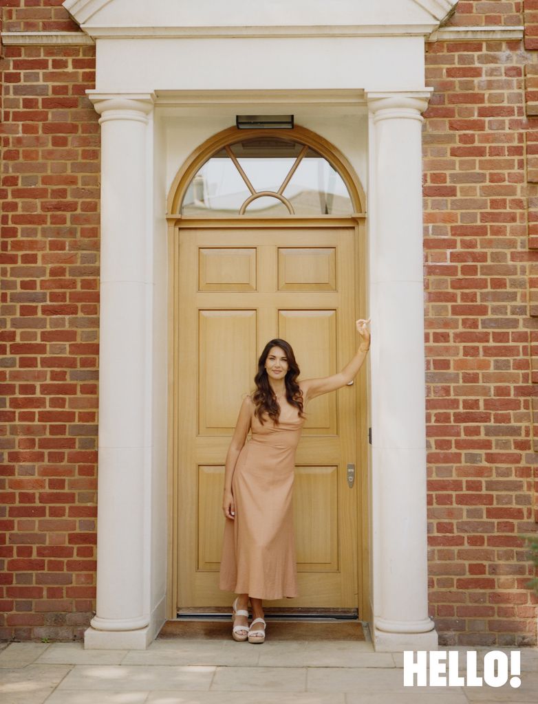 Wearing a Eudon Choi tan strappy dress in front of her stunning front door