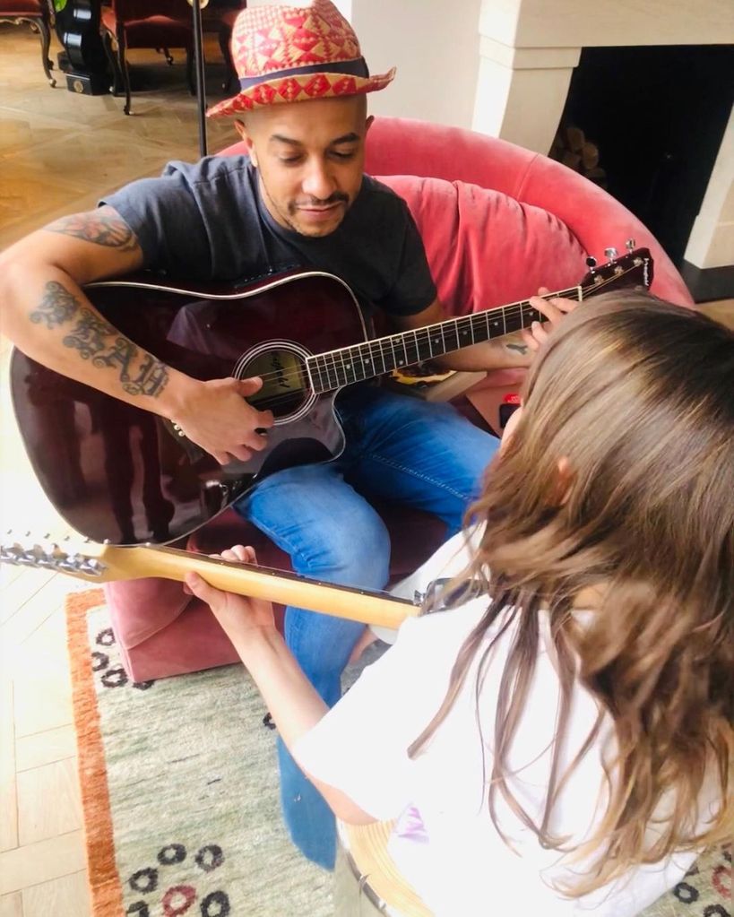 Jade Jones playing guitar with his child Tate