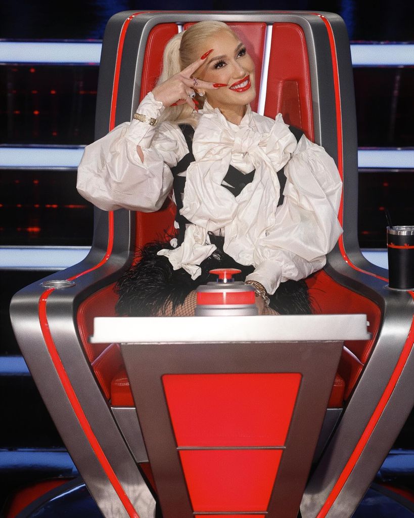 Gwen Stefani in red chair in white shirt and black bodice