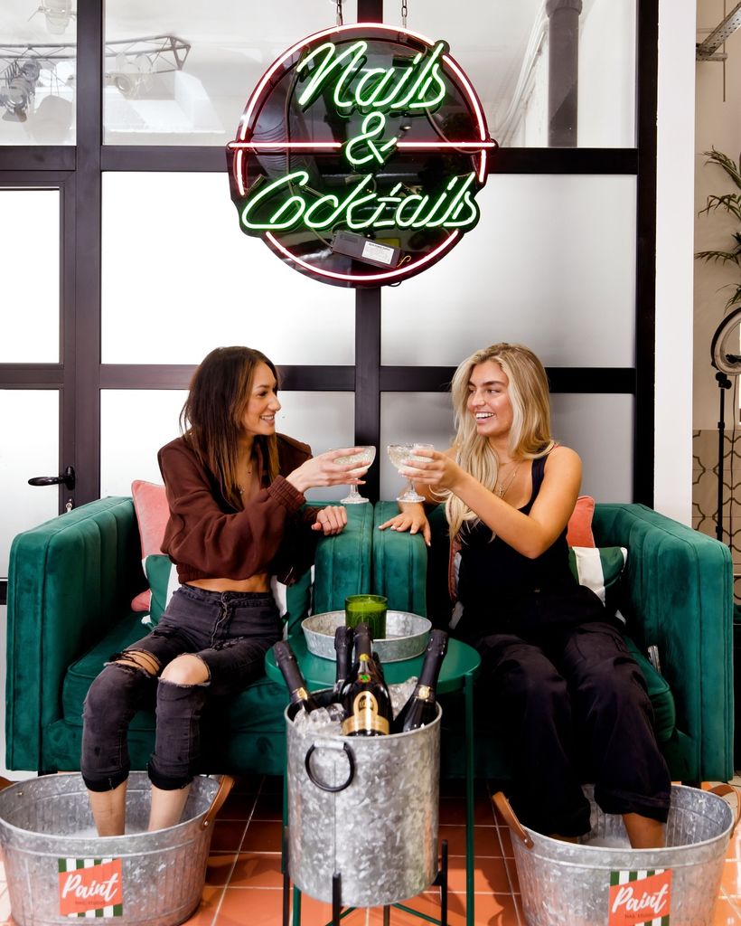 Two ladies have a pedicure and cheers Champagne