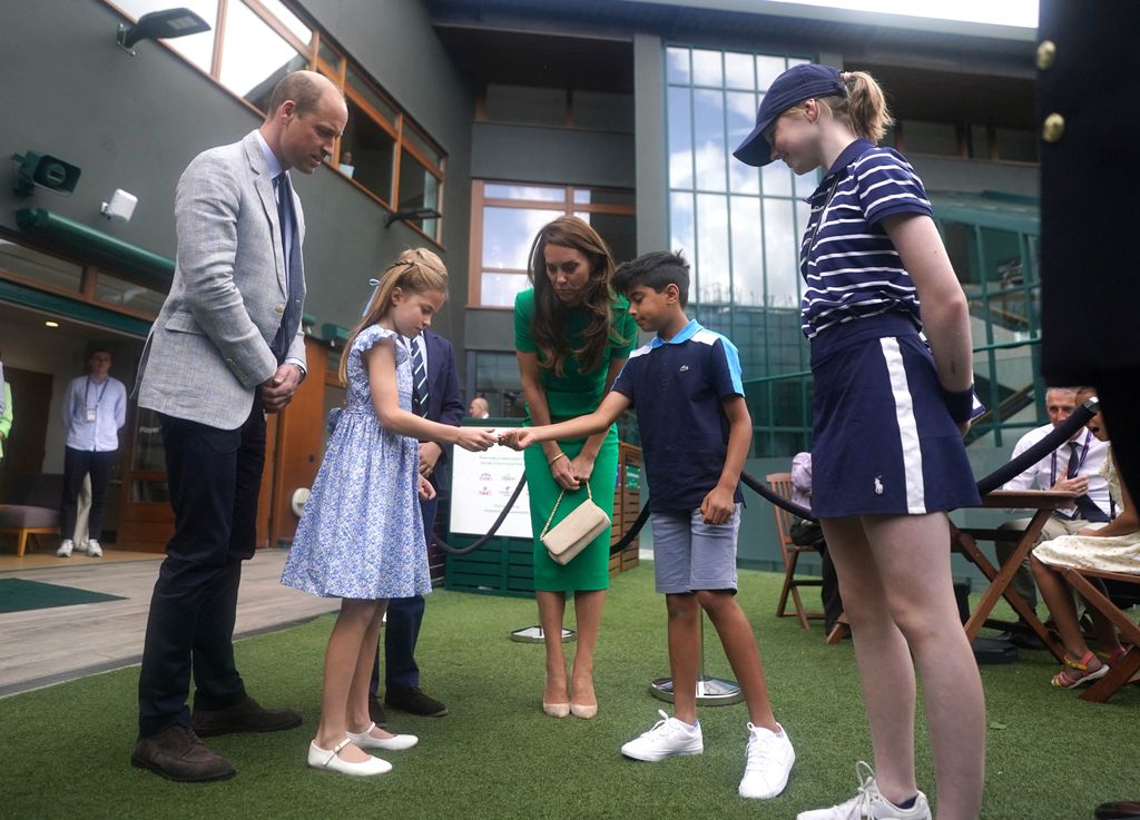 Princess Charlotte holding hand out to Mu'awwiz Anwar (centre right) who performed the men's singles final coin toss 