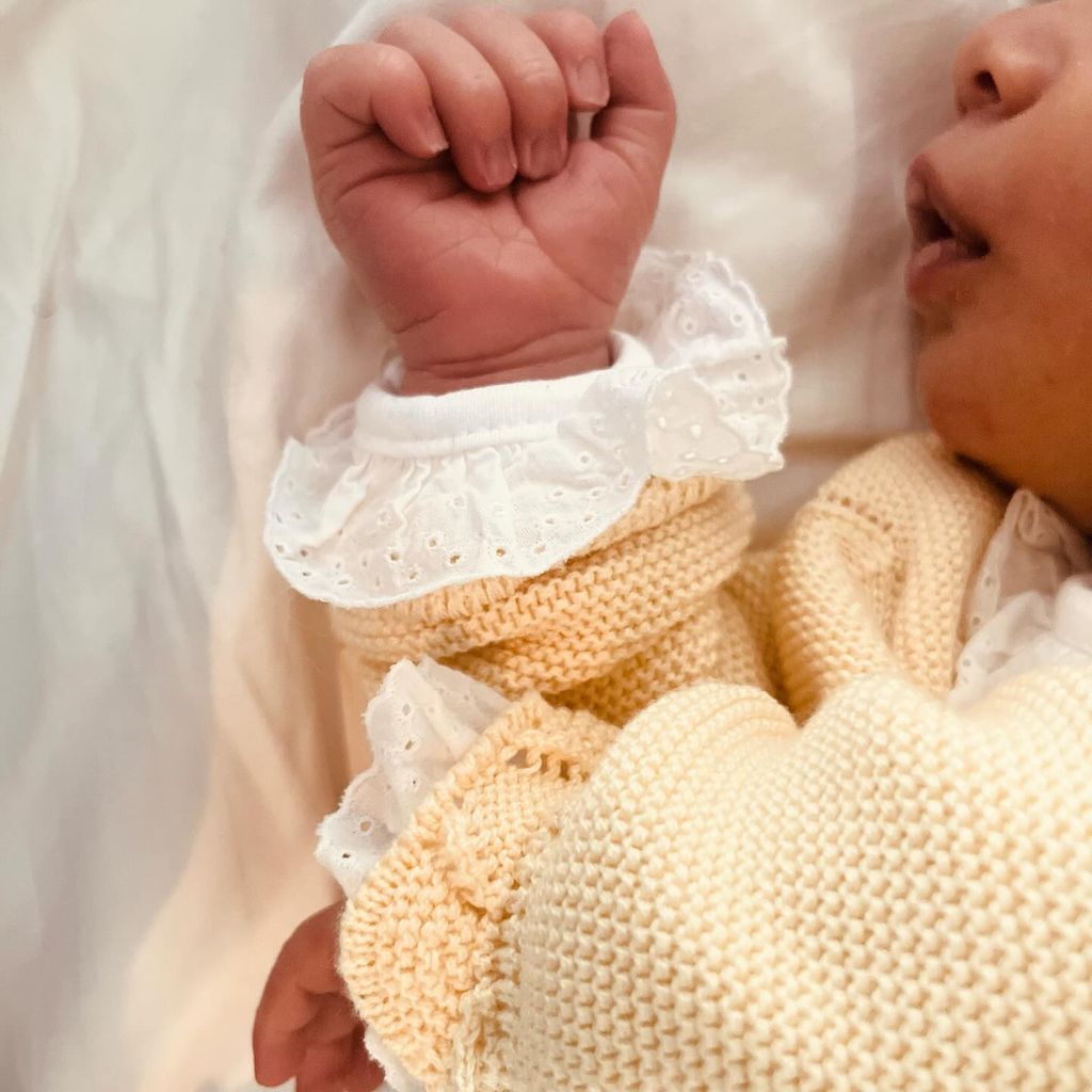 newborn baby in yellow cardigan