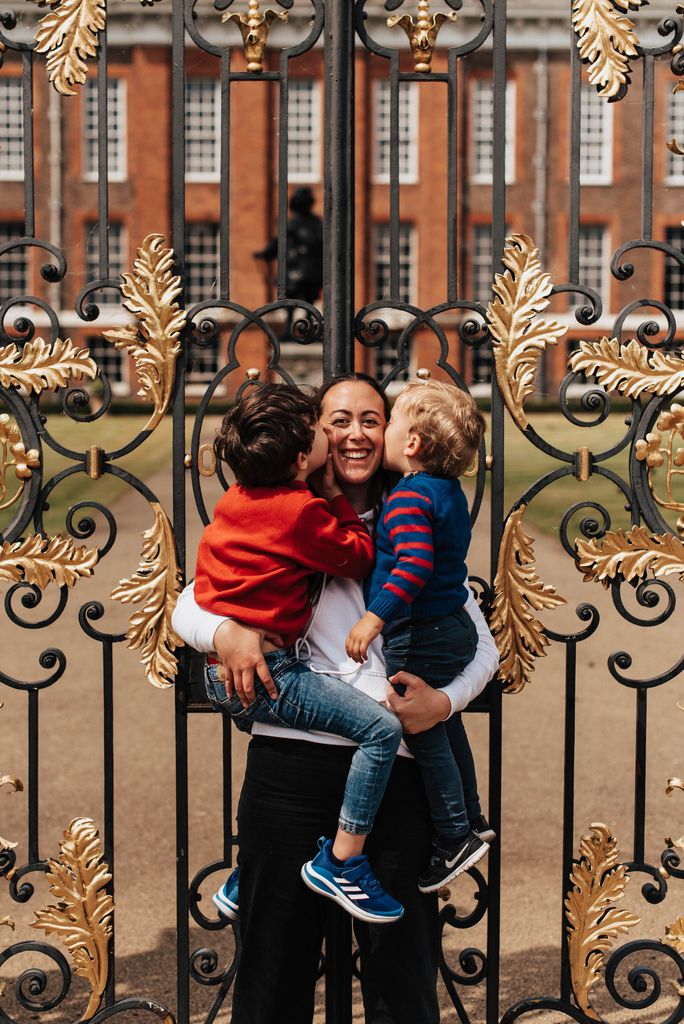 Andrea Caamano holding her children outside the gates of Kensington Palace