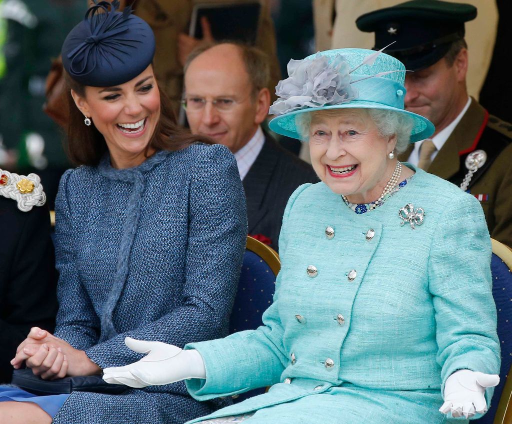 Catherine, Duchess of Cambridge and Queen Elizabeth II sit laughing together while they watch part of a children's sports event while visiting Vernon Park during a Diamond Jubilee visit to Nottingham