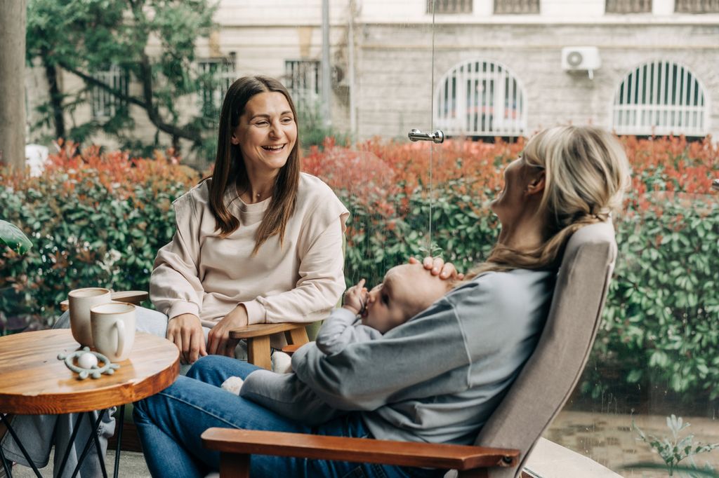Two friends sit in a cafe with a baby