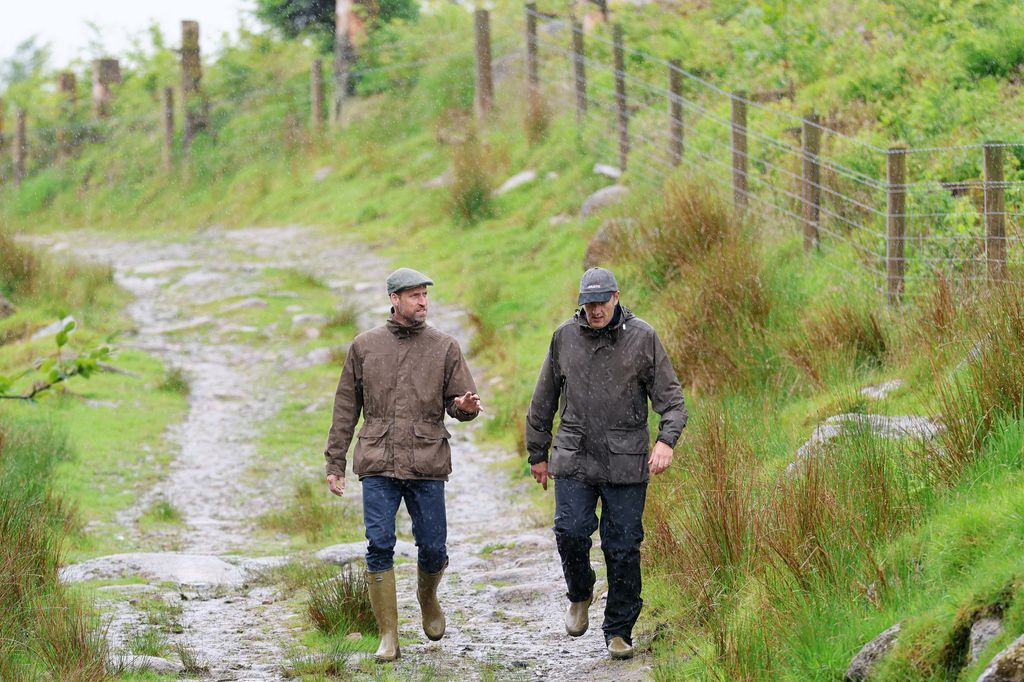 Le prince William marchant à travers le tourbillon avec l'homme en bottes en caoutchouc