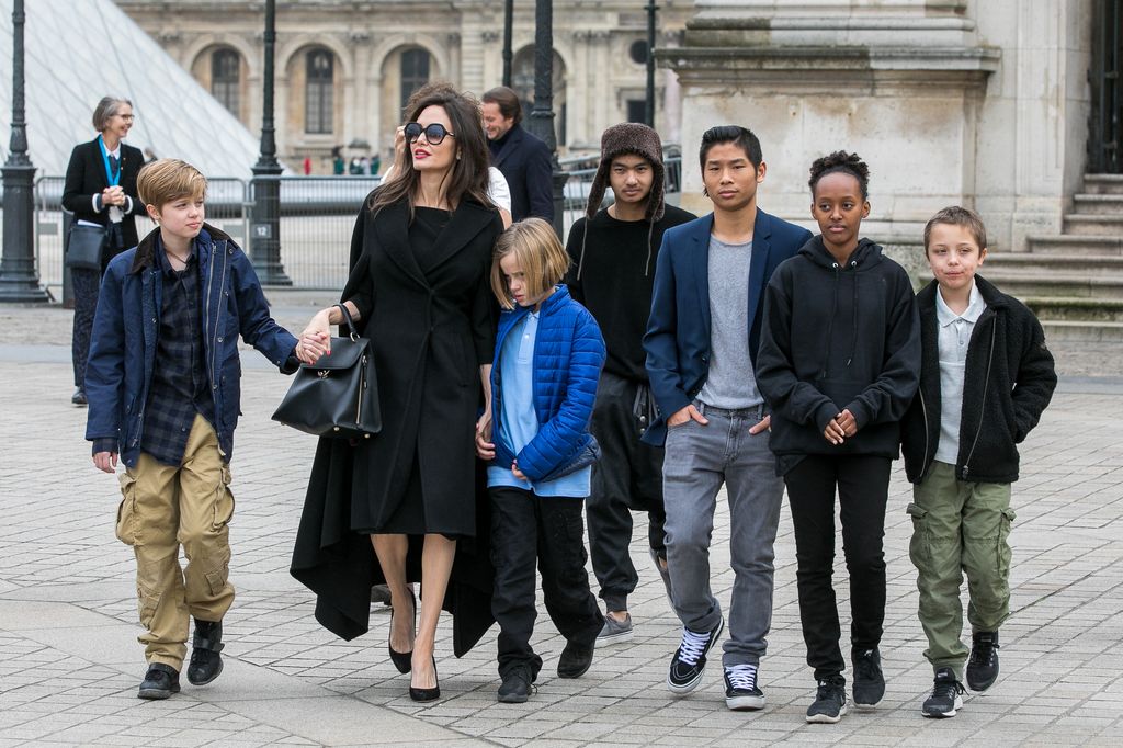 Angelina Jolie walking past the Louvre with sunglasses on in all black, and her children Maddox Jolie-Pitt, Shiloh Jolie-Pitt, Vivienne Marcheline Jolie-Pitt, Knox Leon Jolie-Pitt, Zahara Jolie-Pitt and Pax Jolie-Pitt 