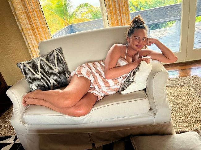 chrissy lounges sideways on a sofa wrapped in what is on closer inspection an orange and white striped towel
