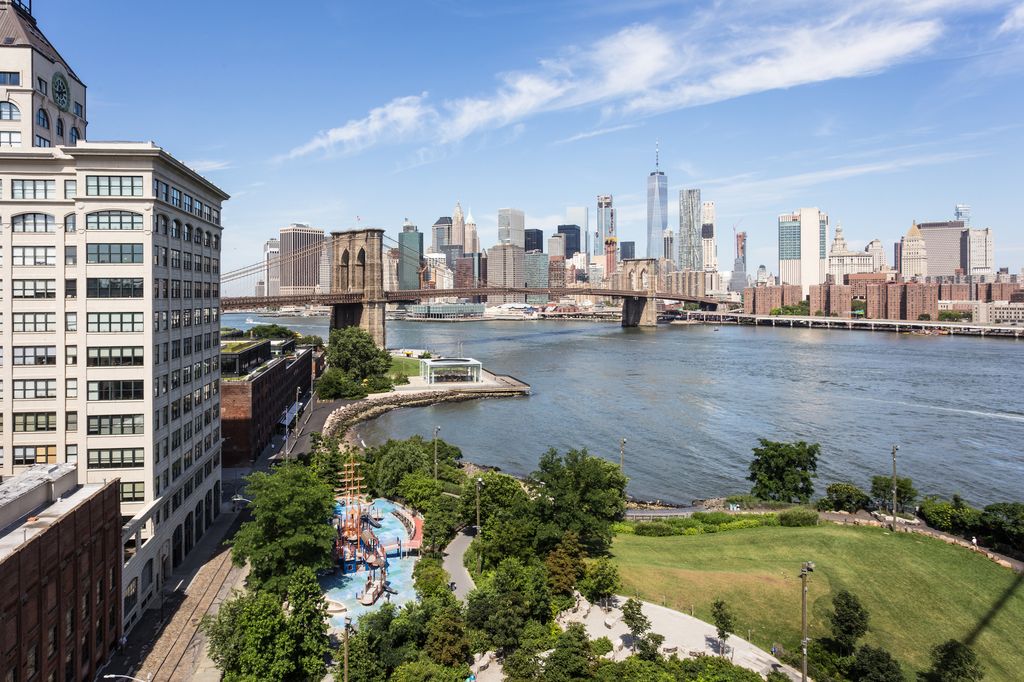 Aerial view of the Brooklyn bridge and its park in DUMBO with Manhattan skyline across the East river in New York city on a sunny summer day.