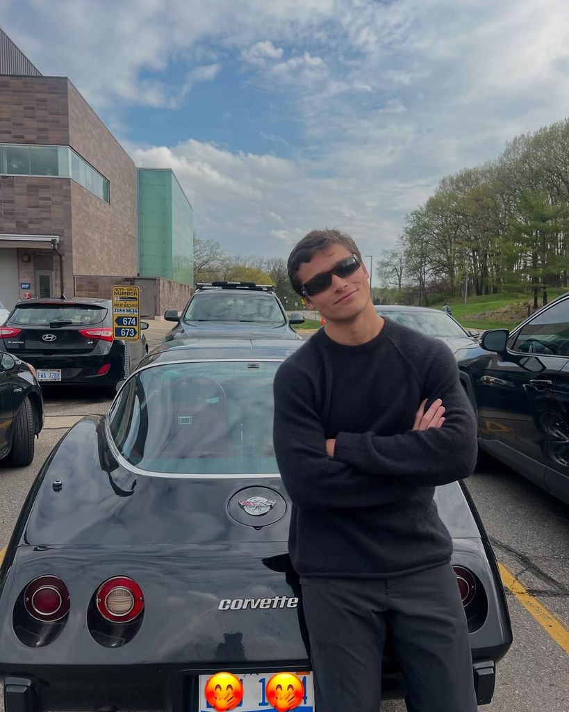 JOaquin leaning against a sports car, sunglasses 