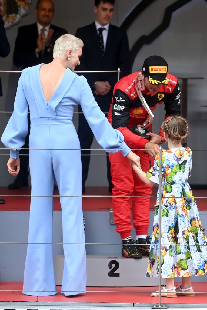 Princess Charlene in backless jumpsuit holding daughter's hand 
