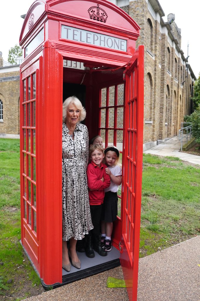 Queen Camilla standing in phone box with schoolchildren