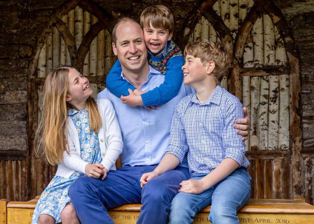 George and Charlotte smiling while Louis hugs father William