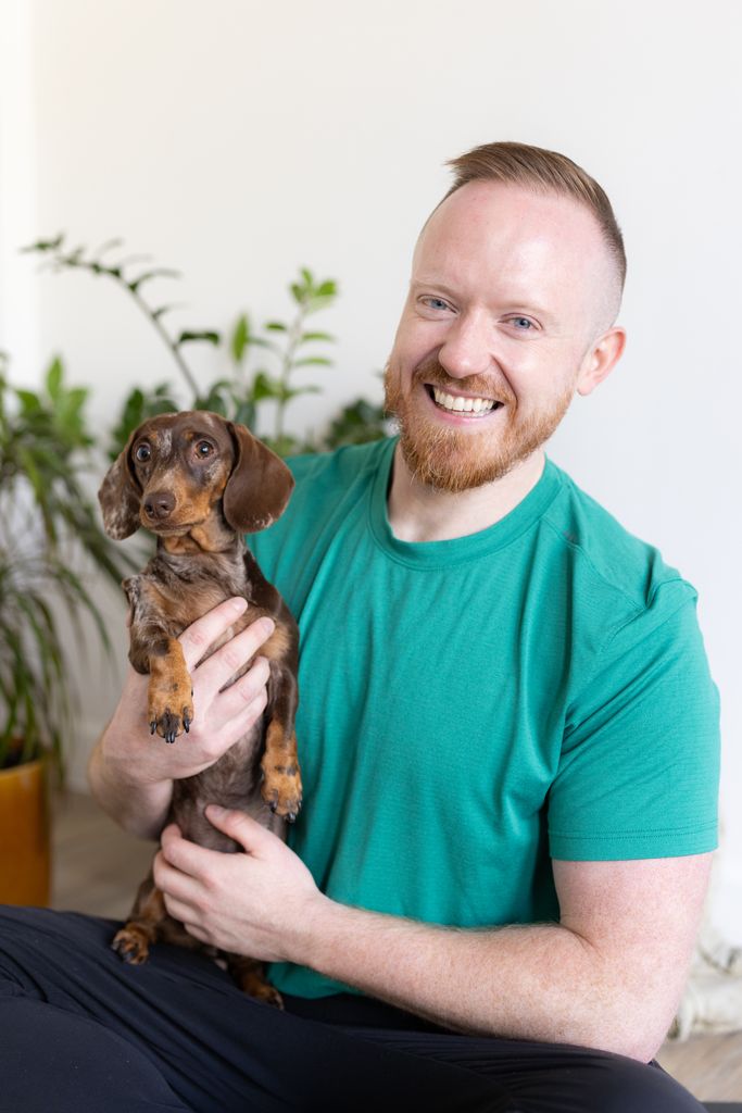 Daniel O'Shaughnessy in a green top holding a sausage dog puppy