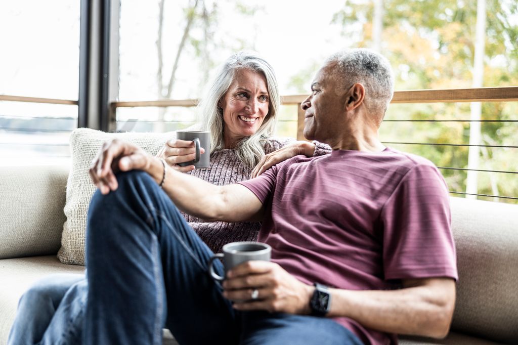Senior couple having coffee and embracing on back porch of vacation home