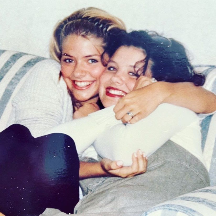 A photo of Kelly and Holly Willoughby hugging whilst sitting on the sofa