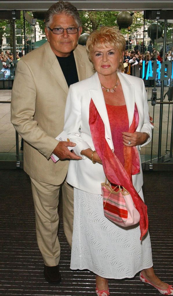 Gloria Hunniford in a white and red suit with her husband Stephen Way in a cream suit