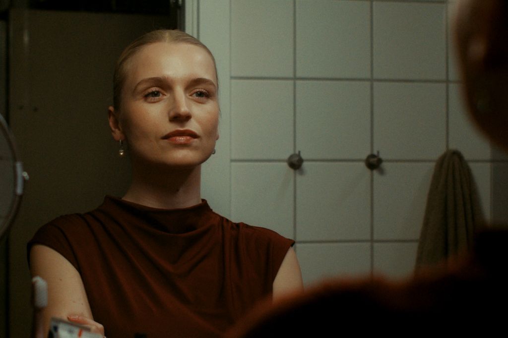 young woman looking in bathroom mirror