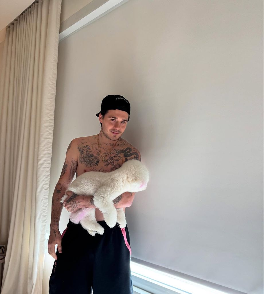 brooklyn beckham posing topless and holding white fluffy dog in room 