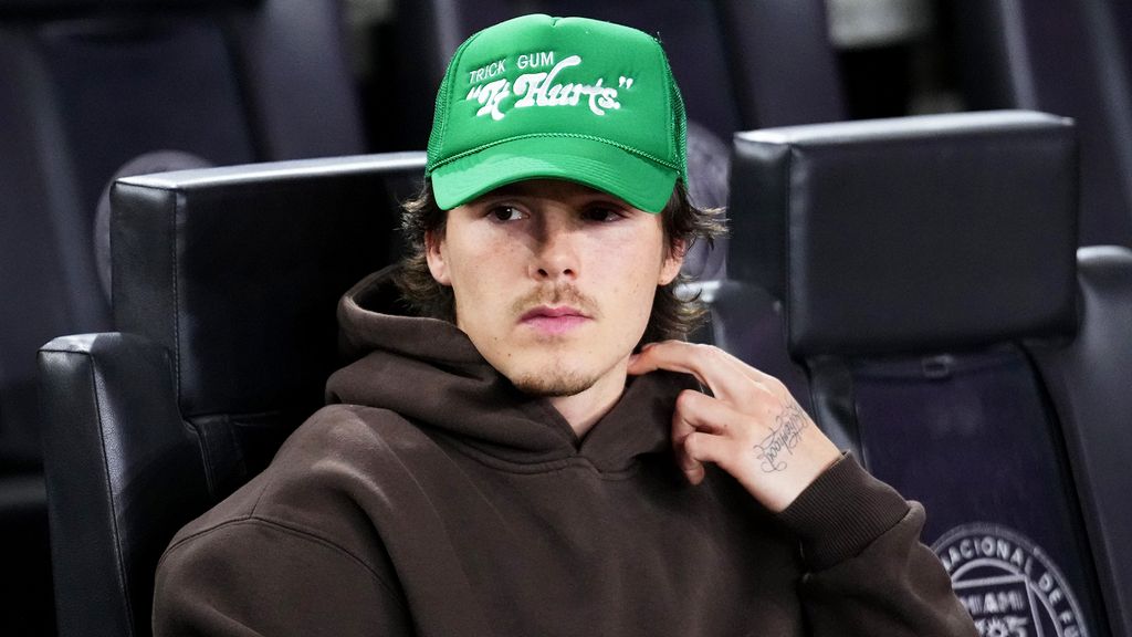 Cruz Beckham wearing a brown hoodie and bright green cap