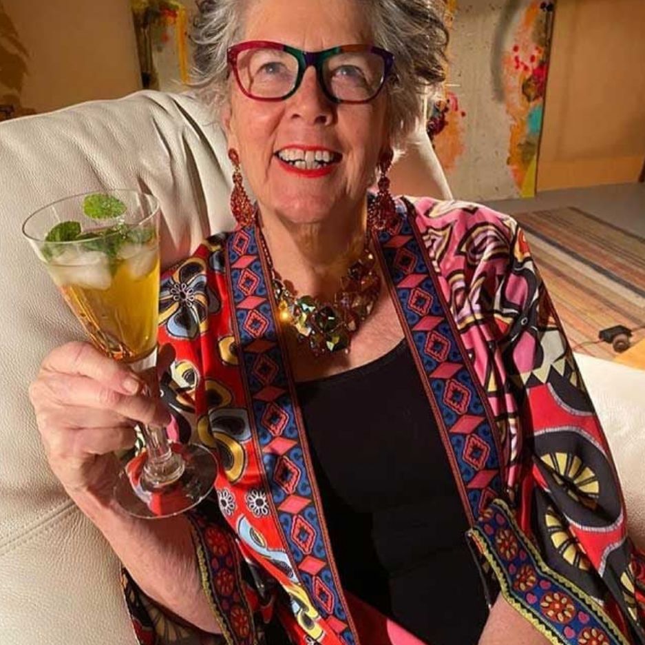 Prue Leith in an armchair with a glass of alcohol