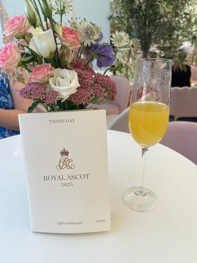 Royal Ascot programme and glass of bucks fizz next to bouquet