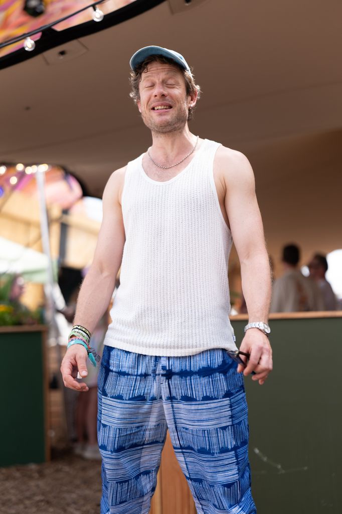 James Norton in a white sleeveless top and blue trousers