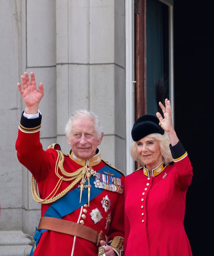 King Charles III and Queen Camilla waving on the royal balcony at Buckingham Palace