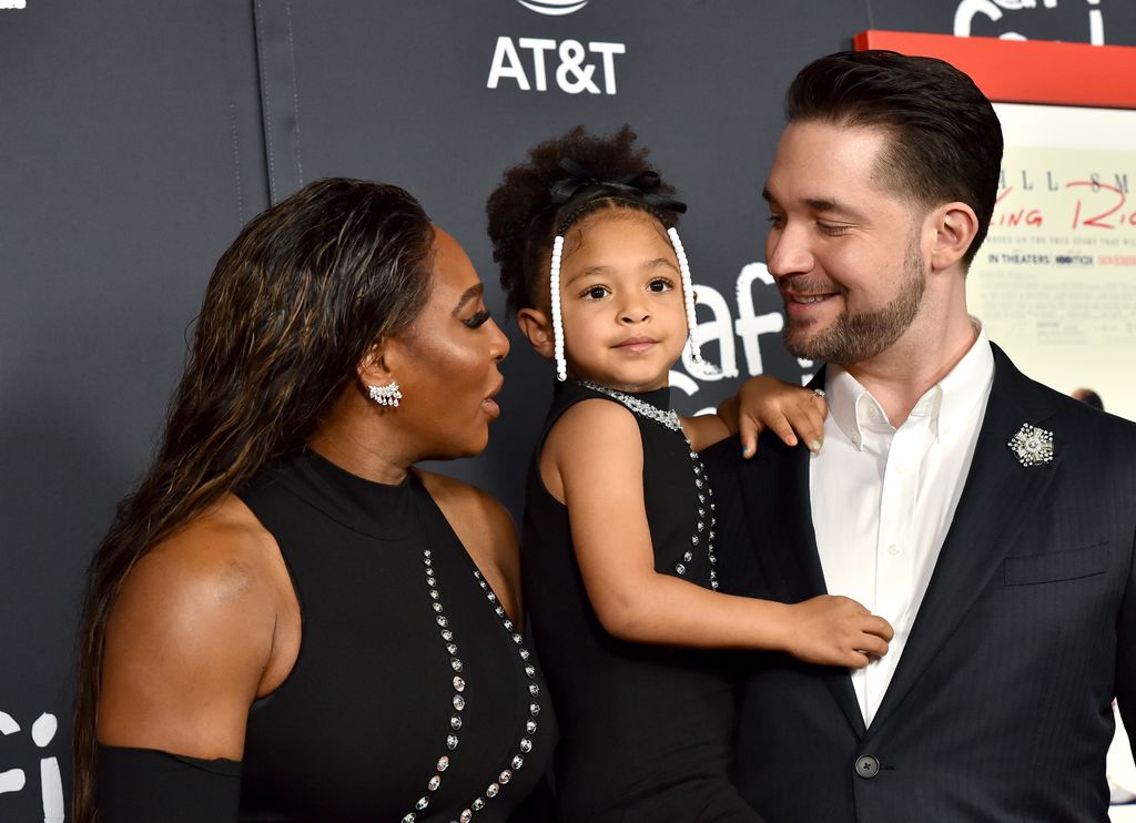 Proud parents Serena and Alexis with their daughter at a red carpet event, Alexis is holding Olympia in his arms