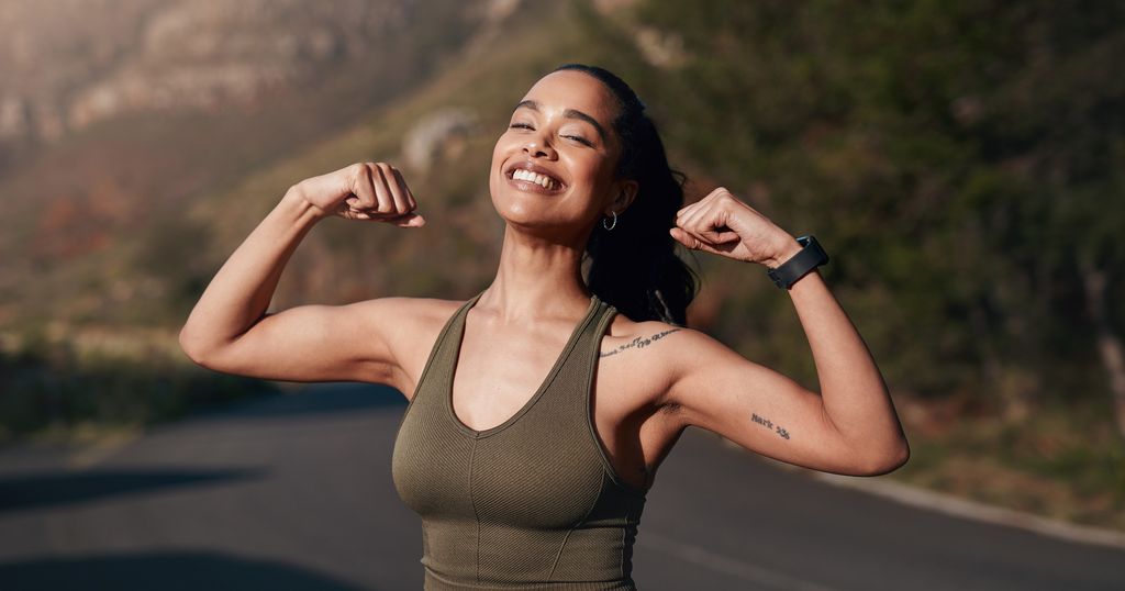 Fitness, strong and woman with muscle, happy outdoor with runner and cardio with smile, healthy and active lifestyle. Running, exercise and body training, flexing biceps and arms with sports in city