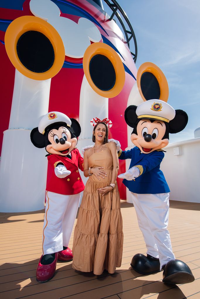 A pregnant Janette Manrara posing with Mickey and Minnie Mouse