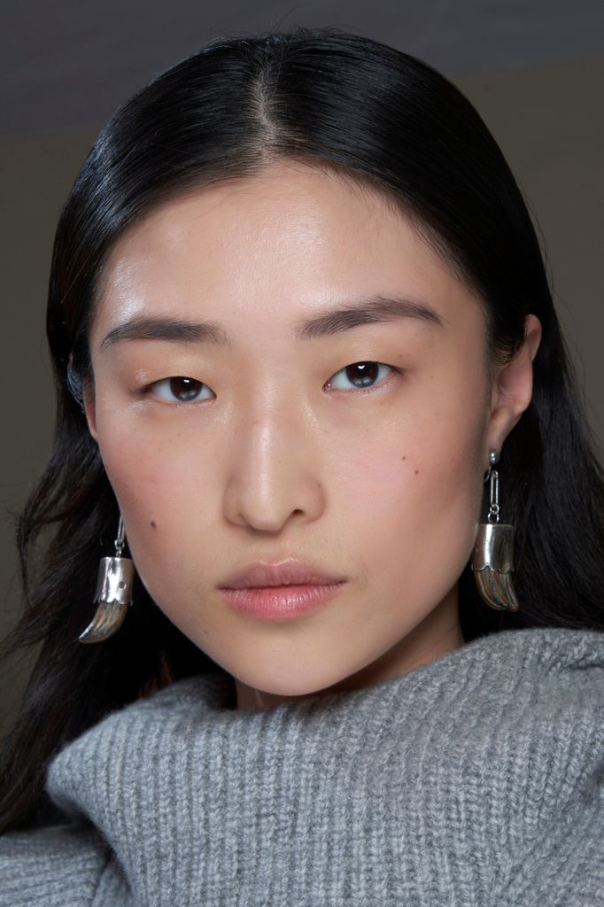 woman with clear skin wearing a grey jumper