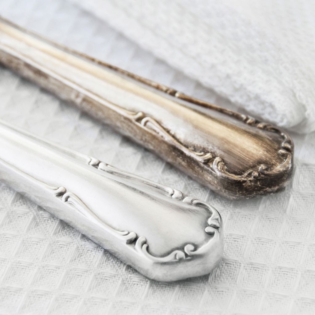 A clean silver and tarnished silver cutlery