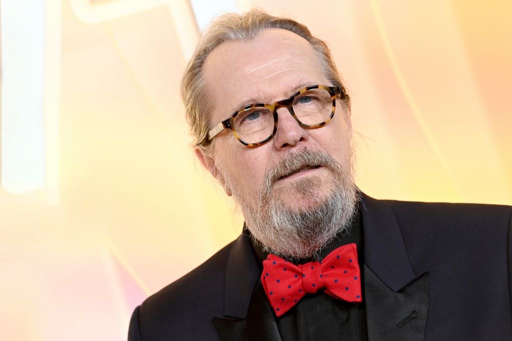 Gary Oldman in a black suit and a red bowtie
