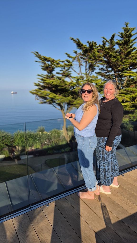 two women smiling on a balcony in the sun