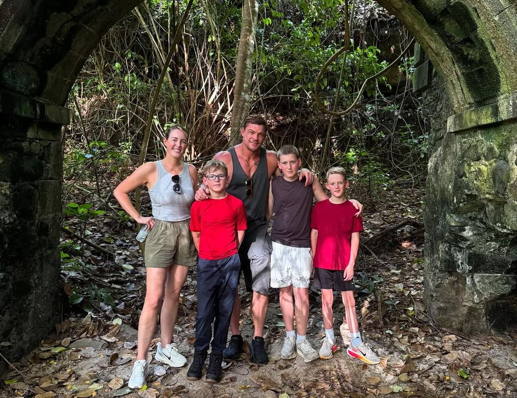 Alan and Catherine pose with their boys in a wooded area while on vacation 