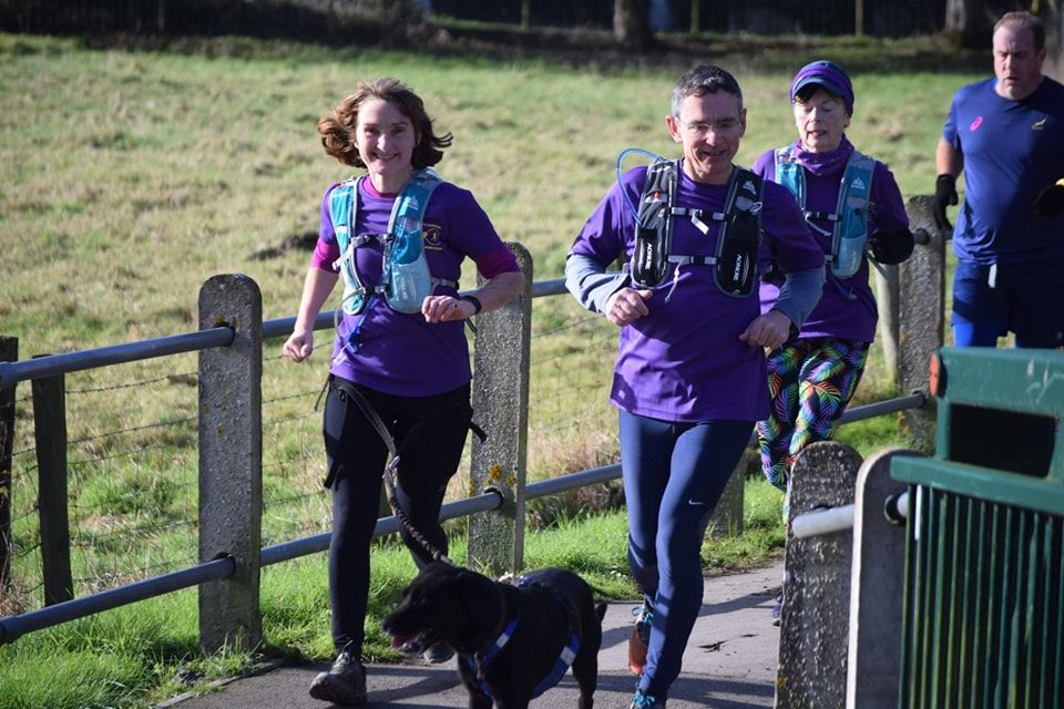 group of people and a dog running outdoors 