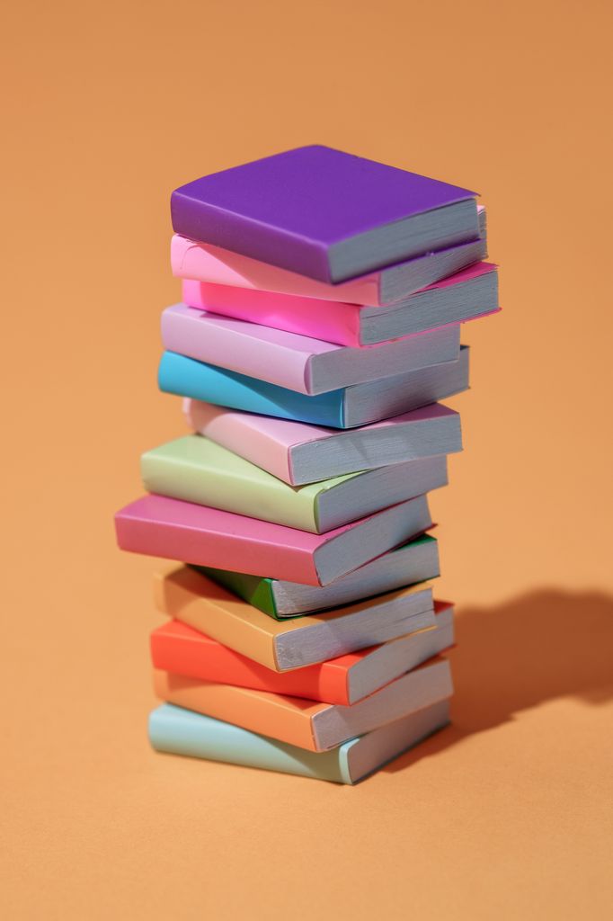 Tall stack of books in various colours against an orange background