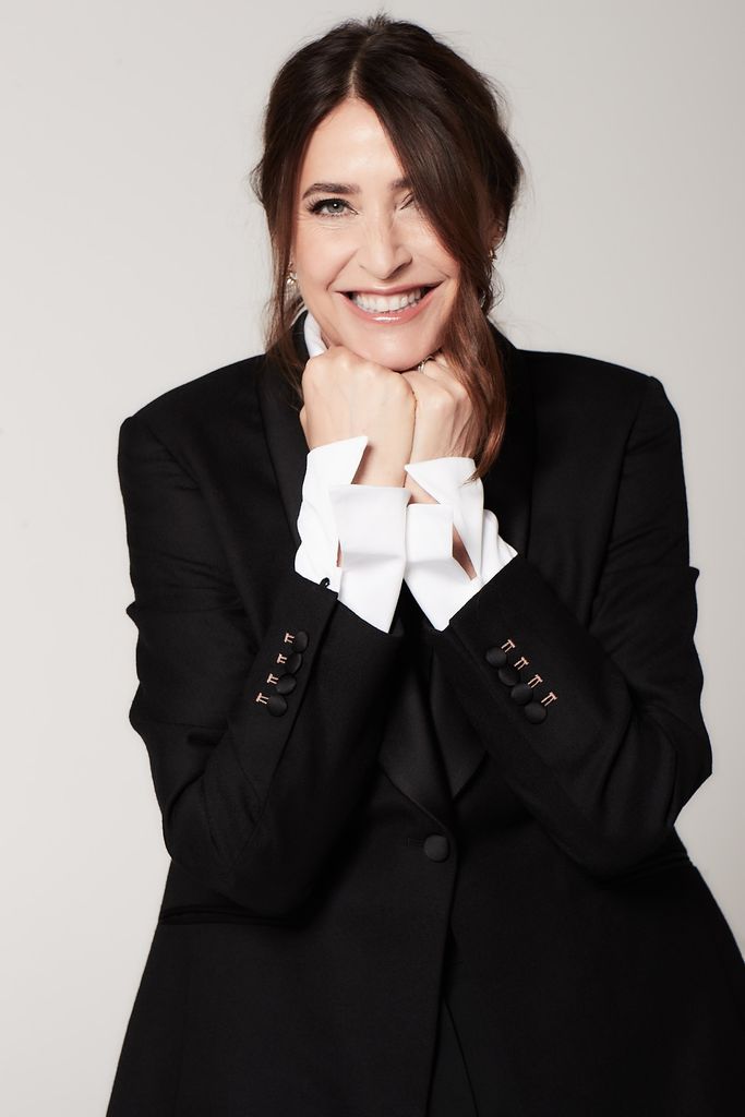 Lisa Snowdon smiling in a black blazer and a white short