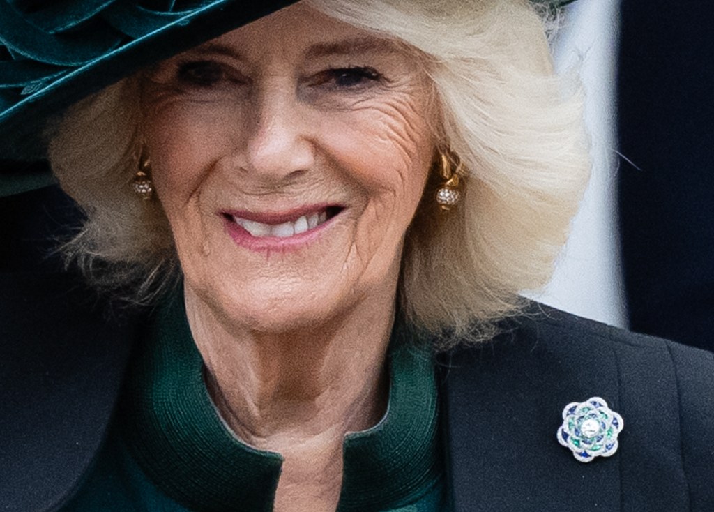 Camilla sorrindo usando broche da Rainha Mary