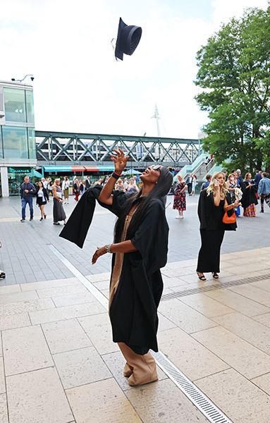 Naomi Campbell throws her mortar board in the air