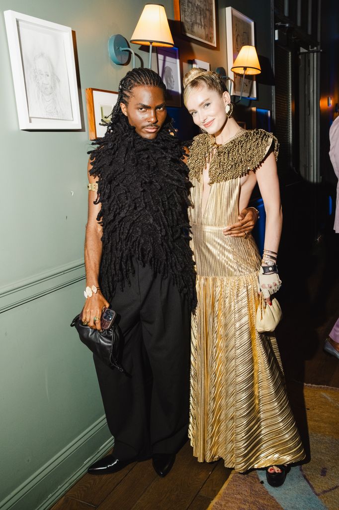 McKinley Guidry in pleated gold gown poses with Curtis Atanga in textured black top and wide-leg trousers at 2025 Met Gala after-party.