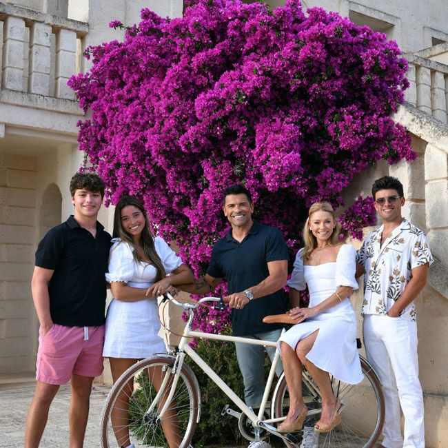 two adults and three teenagers stand under a pink bougainvilla tree
